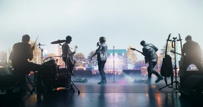 Talented Rock Band Performing a Live Set on Open Air Stage with Fire Pyrotechnics. Young Musicians Playing a Concert at a Festival, Singing Hard Rock Songs at an Indie Event. Back View