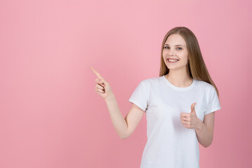 Attractive caucasian young blonde woman in casual white t-shirt smiling, showing thumb up and...