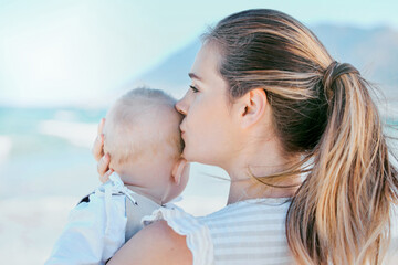 Kiss, mom and baby on beach together for care, love and support or happiness in nature. Family, child and woman or mama outdoor for childhood, development and adventure with comfort in morning