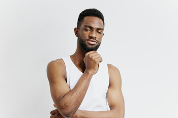 Thoughtful african american man in white tank top pondering with hand on chin in contemplative pose