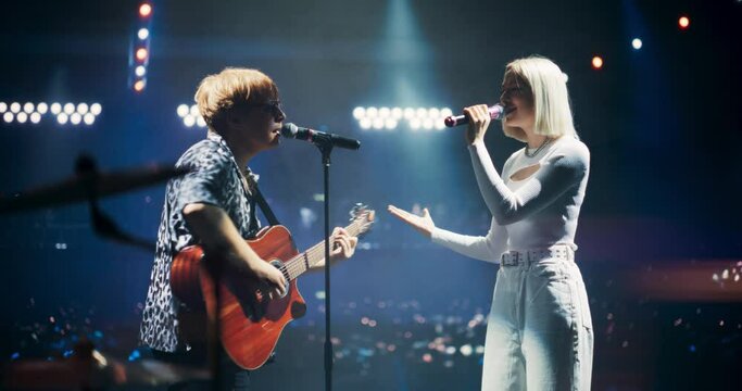 Pop Duo Collaboration With a Male Singer Playing Acoustic Guitar and Female Star Singing on Stage. Folk Guitarist Strums Passionately While RnB Female Performer Sings with Heartfelt Emotion