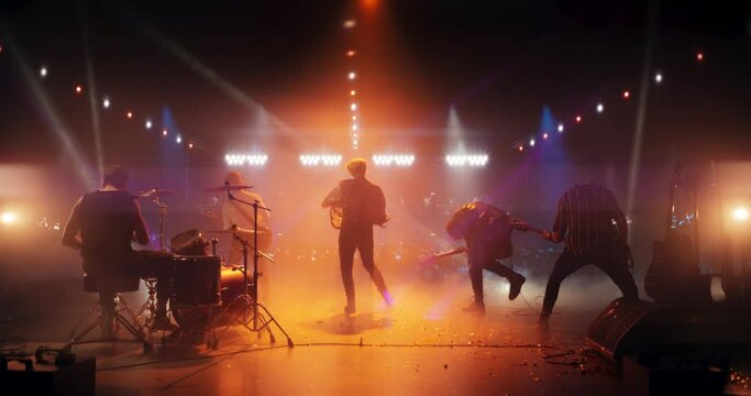 Talented Rock Band Performing a Live Set on an Indoors Stage with Fire Pyrotechnic Effects. Young Musicians Playing a Concert at a Festival, Singing Hard Rock Songs at an Indie Event. Back View
