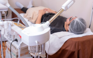 A male customer undergoes a steaming treatment to open up the skin pores. Facial procedure at a...