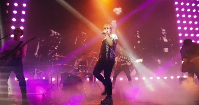 Energetic Rock Band Performing on a Nightclub Stage with Dynamic Lights, Animated LED Screen and Special Effects. Rock Music Artists Creating a Unique Show Experience With Powerful Alternative Music