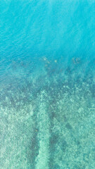 Drone shot birds eye view of a beautiful blue green sea with waves and sand beach in Thailand
