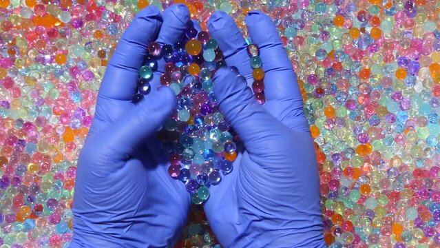 Hands smoothly pick up a multicolored orbis on the background of a lot of colored orbis. And slowly scatter orbis. View from above. ASMR. Part10.14