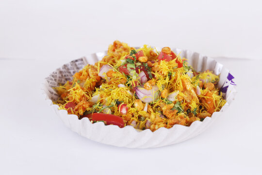 Bhel Puri is a savoury snack/Chaat item from India. It is made of puffed rice, vegetables & tangy tamarind sauce. Popular road side food. Served in bowl / plate over moody background. Selective focus