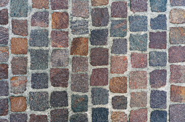 Stone pavement texture from red granite cubes, cobblestone street background top view