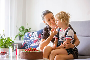 Mother and child, toddler boy, watching movie on a tablet, cake and flowers