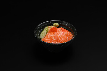 Bowl of salmon Donburi served with wasabi and prickled ginger on black background. Japanese food concept