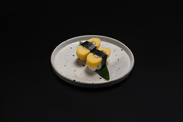Japanese nigiri Tamago sushi wrapped with nori seaweed on black background. Japanese food concept