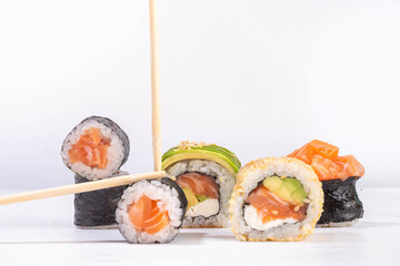 Creative  Japanese seafood sushi set background containing sushi rolls, maki, gunkans with chopsticks on white table
