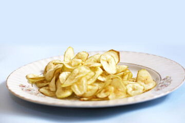 Banana chips. Banana wafers. Dried Black Pepper Banana Chips or Banana Wafers top view isolated white plate in white background.