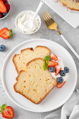Delicious vanilla pound cake served with fresh berries and whipped cream on a gray concrete background. Selective focus, copy space.