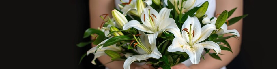Fototapeta premium A woman holds a bountiful bouquet of pure white lilies