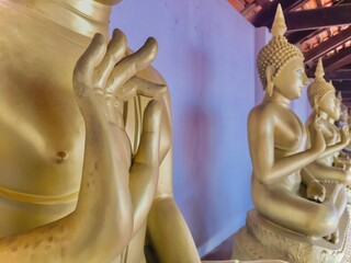 Close up of golden hand of Buddha statue in Phra Borommathat Sawi Temple.