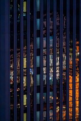 Fototapeta premium Close-up view of a modern building's glass facade reflecting city lights at night