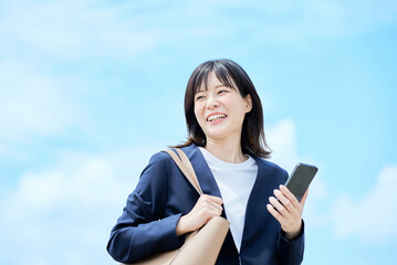 スマートフォンを手に出勤する若い女性