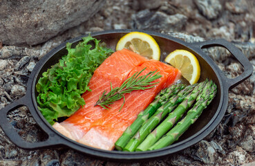 Healthy baked salmon steaks with greens and asparagus in a black cast iron skillet. A delicious low-carb breakfast.