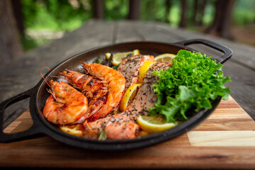 Healthy baked salmon steaks with greens and asparagus in a black cast iron skillet. A delicious...