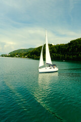 Sailing boat with white sails , roaming around the lake