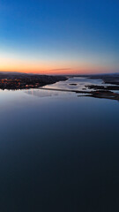 Beautiful yellow orange reddish sunset at dusk stretching over a lake in which slight reflections are visible