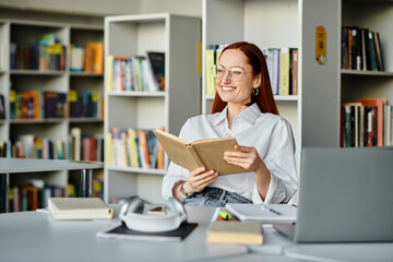 A redheaded woman engrossed in a book, surrounded by shelves of books in a library, absorbing...