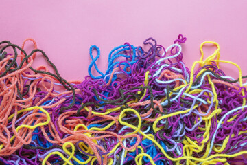 Colorful tangled threads on pink background, copy space