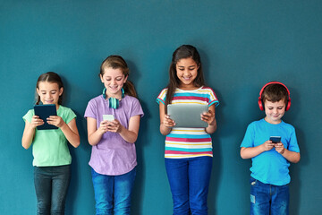 Studio, technology and group of kids for elearning, education and online research with smile. Happy students, girls and boy with digital app of tablet, smartphone and headphone by blue background