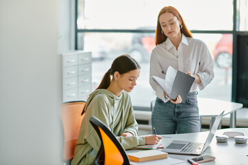 A redhead tutor and a teenage girl engage in after-school lessons at a desk, using a laptop for modern education.