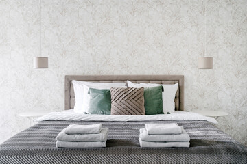Stack of white clean towels on double bed in classic style hotel suite