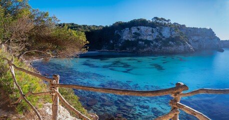 landscape view of the idyllic Cala Macarella in southern Menorca with a hiking trail in the...