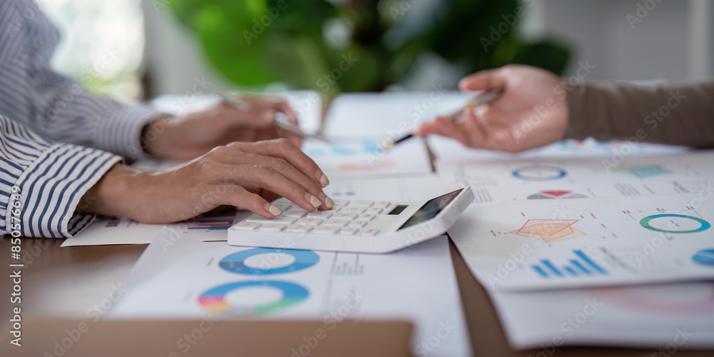 Poster two business professional discussing planning and analysis with charts and calculator in modern offi
