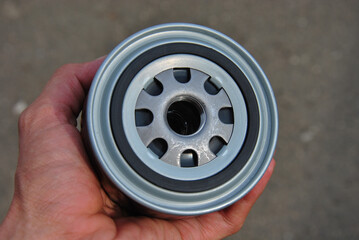 new car oil filter in the hand of a mechanic close-up. blurred background