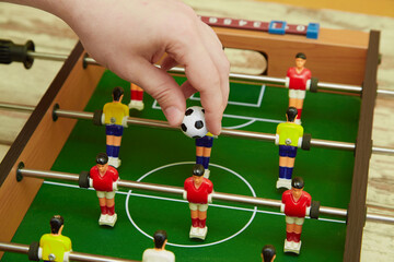 Hand throws the ball into a foosball game, sports table football game, game start