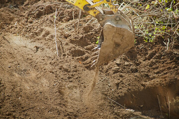 Excavator bucket digging a pit, excavator bucket in soil, close-up