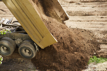 a truck releases a load of soil, demonstrating the unloading mechanism in action.