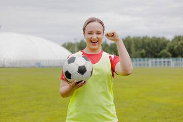 Happy female football player in sportwear celebrating victory, holding soccer ball.