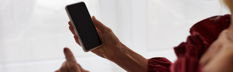 A mature woman in a striking red dress, holding a cellphone.