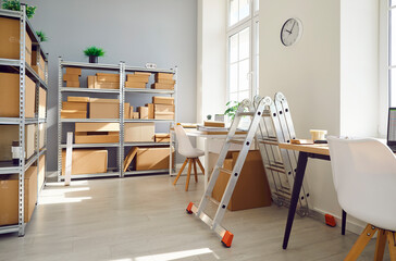 Interior of empty work space with office desk in warehouse with shelves filled cardboard boxes of...