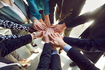 Obraz premium Close up top view photo of diverse business people putting their arms together. Stack of hands of a group of multiethnic company employees. The concept of unity, partnership and teamwork.