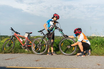 Man cyclist repairing a bike against the background of sky