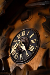 closeup of the dial with roman numerals and hands of a wooden cuckoo clock, time concept