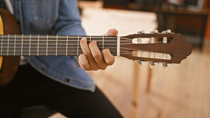 Obraz premium Hispanic man playing guitar in a music studio, focused on his hands and instrument