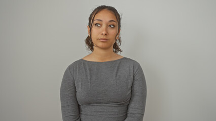 Portrait of a contemplative young hispanic woman isolated against a white wall, exuding beauty and simplicity.