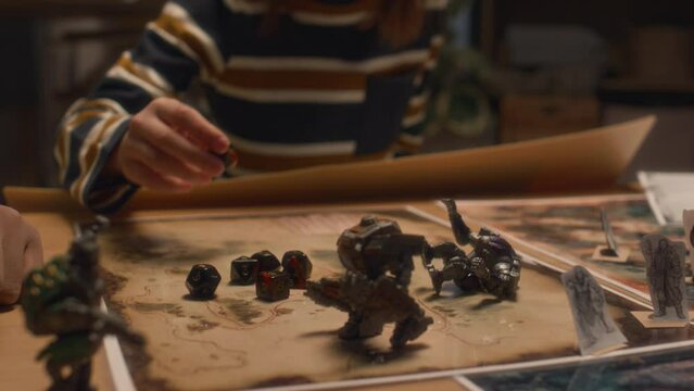 Midsection shot of anonymous child looking at multi sided dice and cardboard characters of tabletop game at home