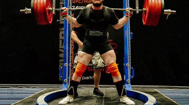 male athlete starting for squat with barbell powerlifting competition