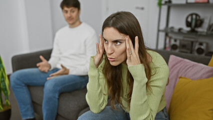 Obraz premium A woman showing stress as a man tries to communicate with her in a modern living room setting.
