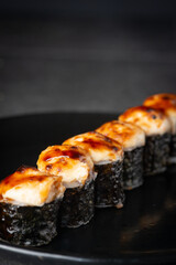 Baked sushi on a black plate