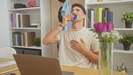 Hispanic man affectionately kisses credit card at a home office setting, signifying financial...